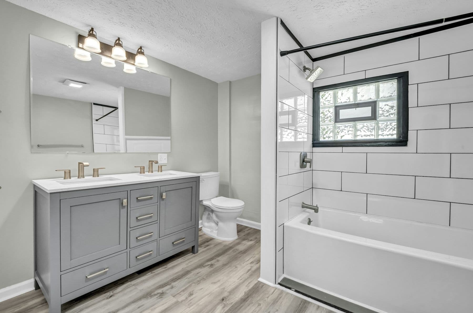 Remodeled bathroom with a gray vanity and a bathtub with full-height white tile