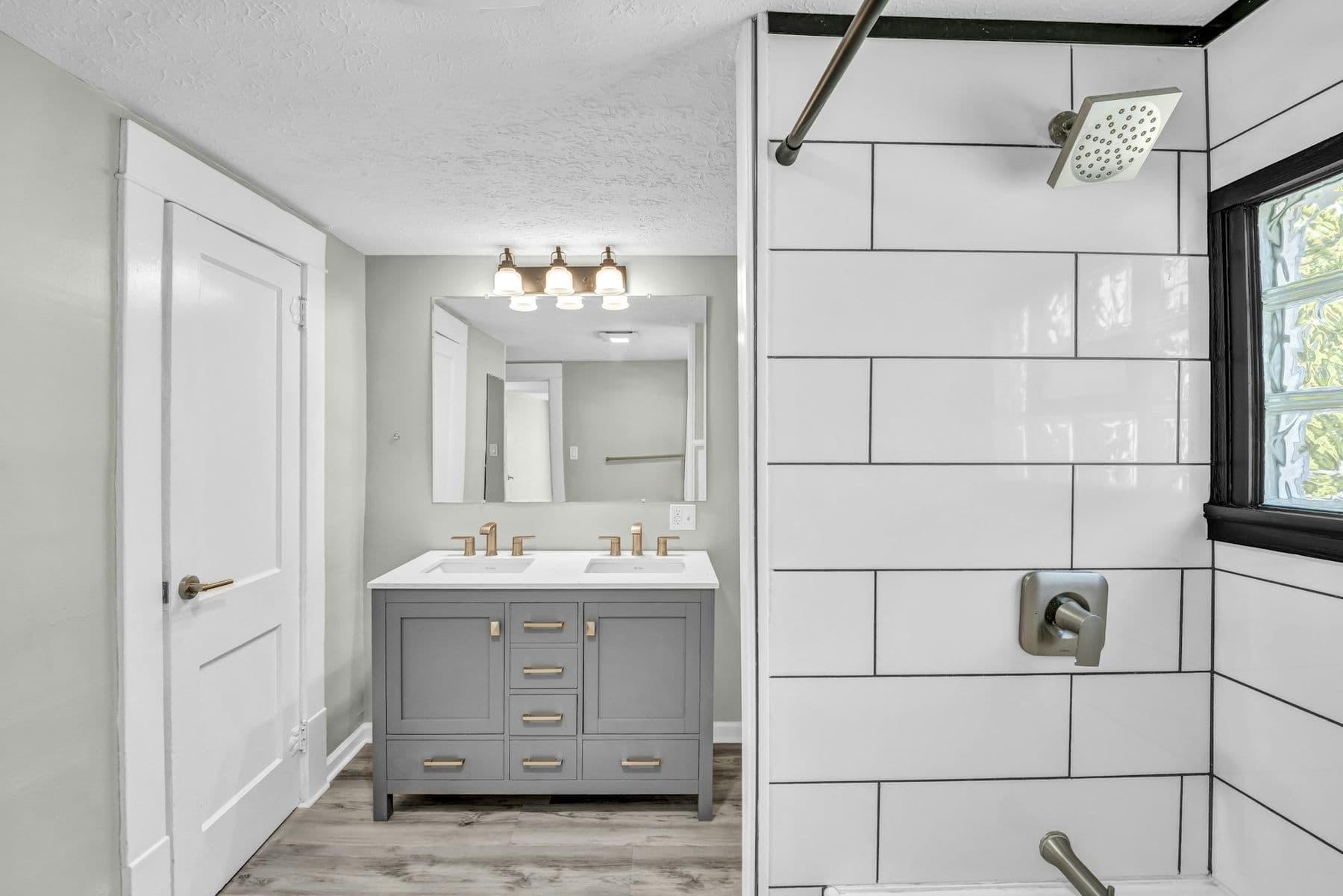 Gray double vanity next to a tiled tub and shower