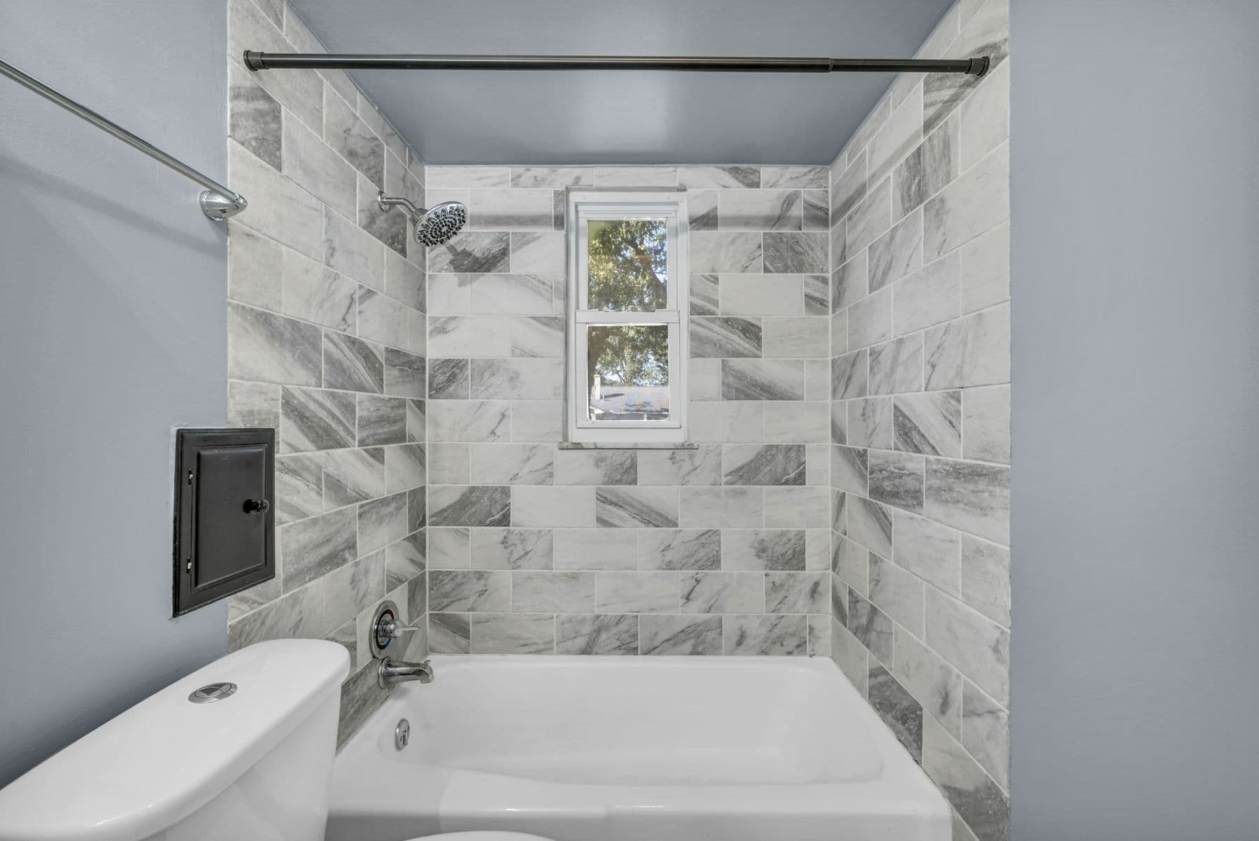 Bathtub with full-height marble-look tile around the tub